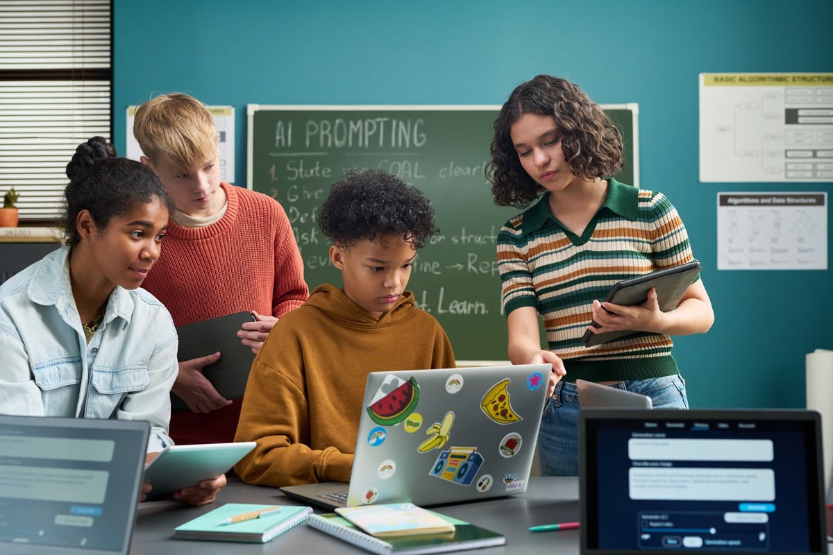 Group of multiethnic teenagers collaborating on laptop in classroom